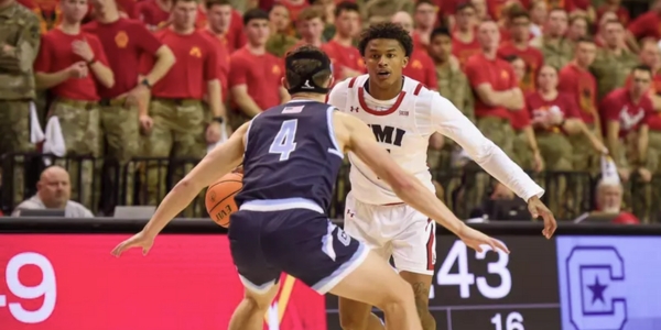 A VMI Basketball player dribbles while being cheered on by the Corps of Cadets in Cameron Hall.