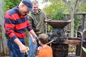 Visitors to the Jackson House Museum participate in free activities on Apple Day, including milling apples.