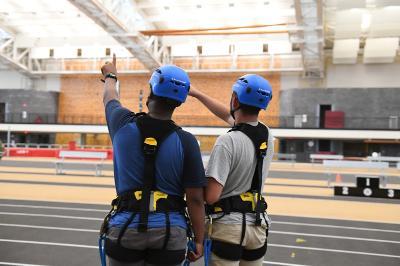 Two COW participants look up 60’ to the indoor high ropes course before confronting it, in the VMI Corps Physical Training Facility.—VMI Photo by Marianne Hause.