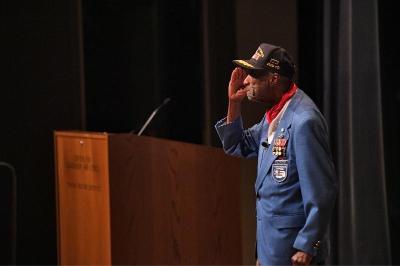 Lt. Col. Enoch “Woody” Woodhouse II, one of the Tuskegee Airmen, salutes the crowd at VMI in Gillis Theater prior to his talk on Feb. 17.—VMI Photo by H. Lockwood McLaughlin.
