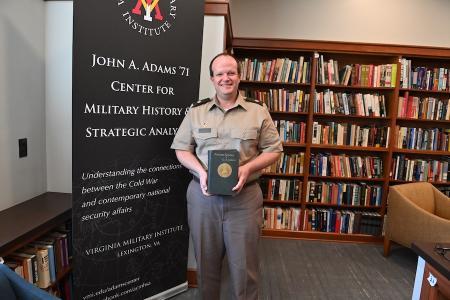 Lt. Col. Joel Christenson ’99 holds the “Personal Memoirs of U.S. Grant,” a treasured part of the book collection recently donated to the Adams Center.