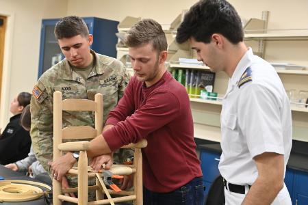 Andrew Hart instructs Joshua Addis ’25 and Luke Cockerham ’26 on splint bottom weave caning during their botany class.