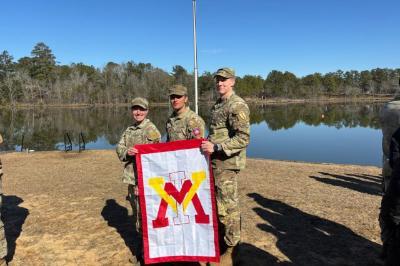 Three VMI graduates hold a VMI flag after completing Ranger School.