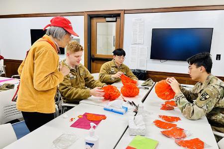 Students (cadets) at VMI, a military college, design crafts during a Global Festivities event on campus (post).