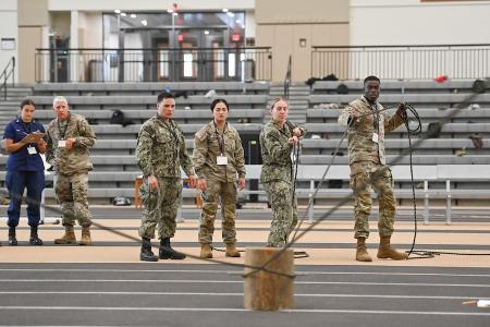 One of the eight teams works together to complete an obstacle in the Leadership Reaction Course in the Corps Physical Training Facility.