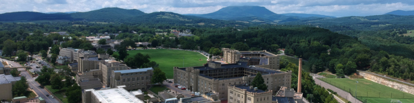 Aerial view looking over post, VMI's historic senior military college campus, known as post, is blanketed in snow and seen from behind barracks towards downtown Lexington, Virginia and the Blue Ridge mountains.