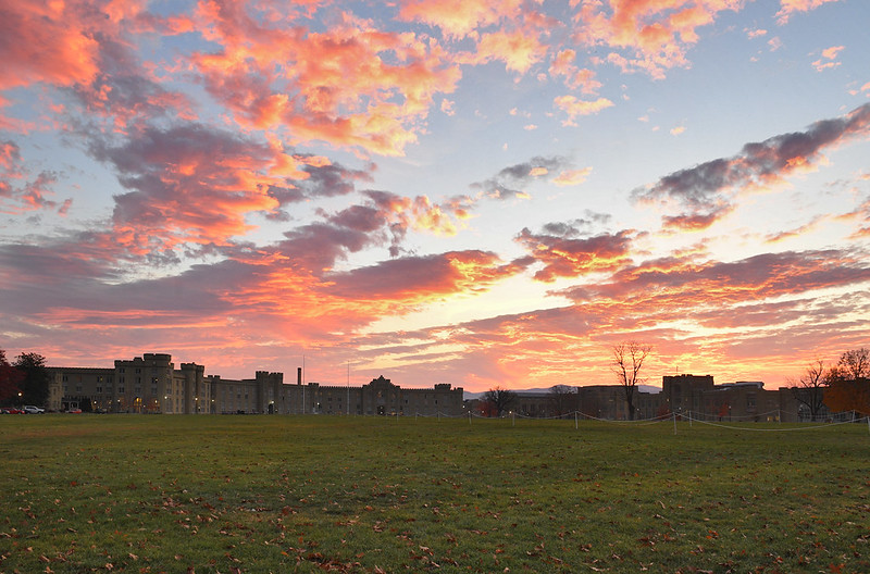 Barracks stands at the rear of campus, with an autumn sunrise in the background.