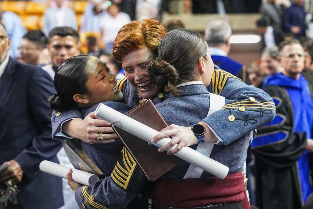 Cadets embrace after receiving their diplomas.
