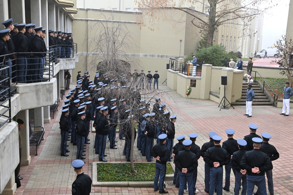 Cadets stand at attention facing a podium in Daniels Courtyard.
