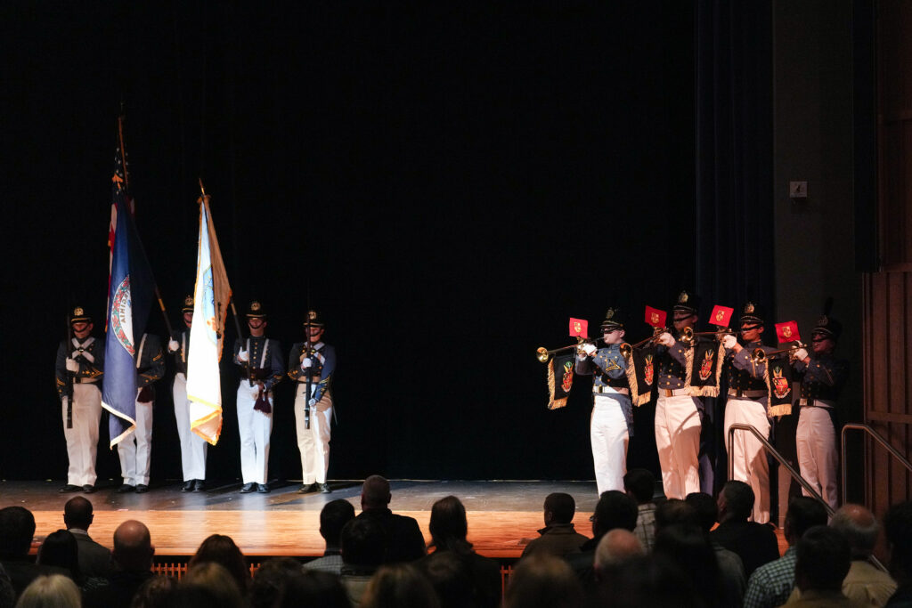 Cadets hold flags while others play trumpets.