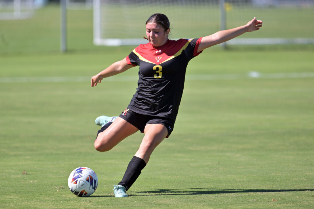 Cadee Hegarty kicking a soccer ball on the field, playing for Virginia Military Institute.