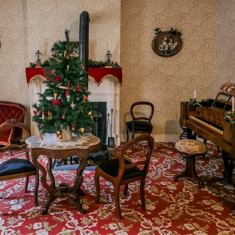 A room in the Jackson House Museum is decorated for Christmas with festive touches including a tree.