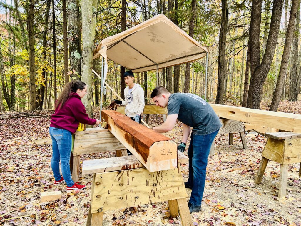 A group of cadets stain wood at the China Folk House Retreat in Harpers Ferry, West Virginia.