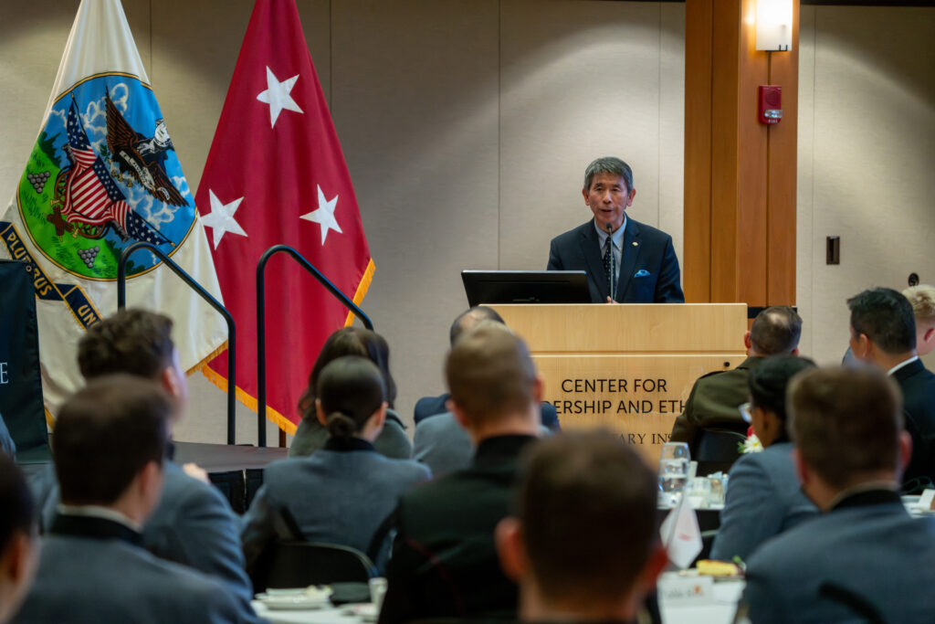 Event attendees listen as Adm. Sakai speaks at a podium.