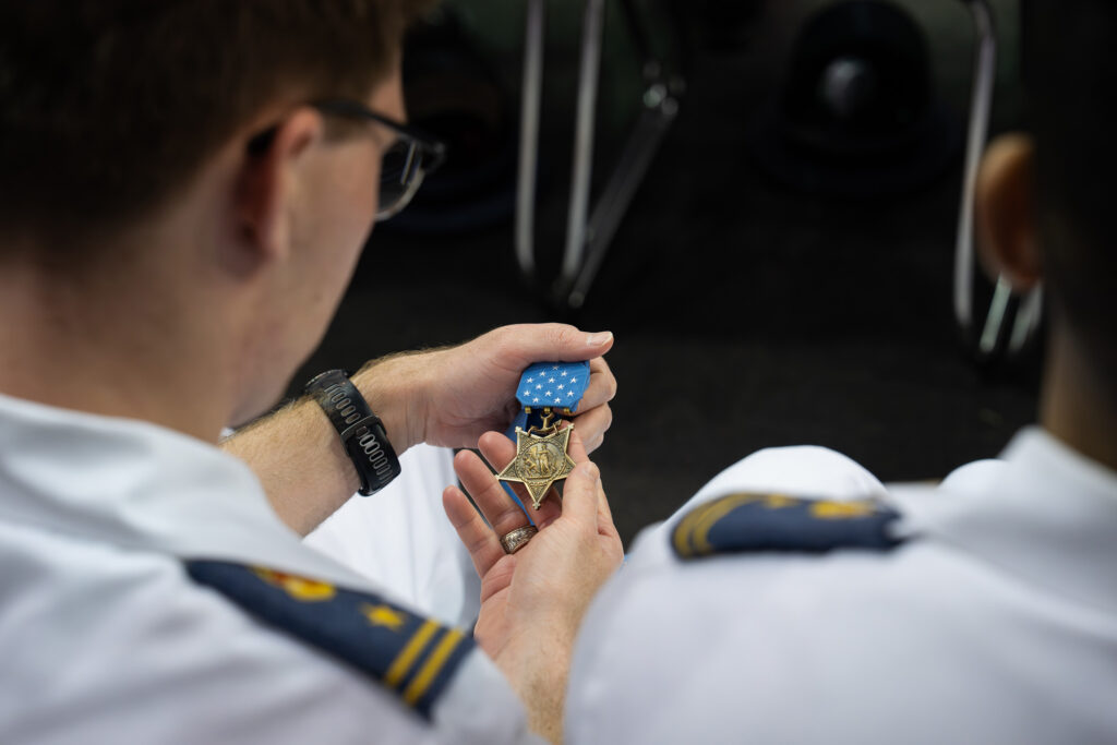 A cadet holds a Medal of Honor with blue ribbon in his hand.