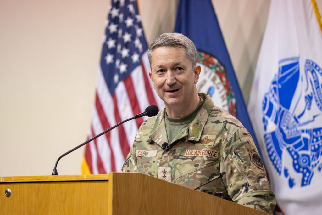 Gen. Dan Caine '90 speaks at a podium wearing Air Force OCPs.