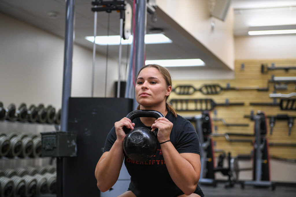A woman does a goblet squat with a kettlebell.