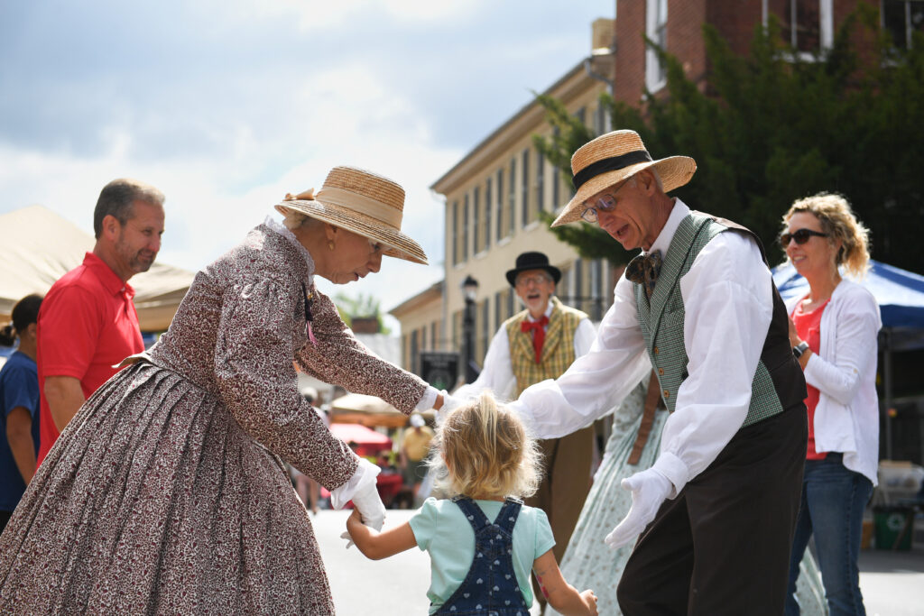 Costumed interpreters dance with event attendees.
