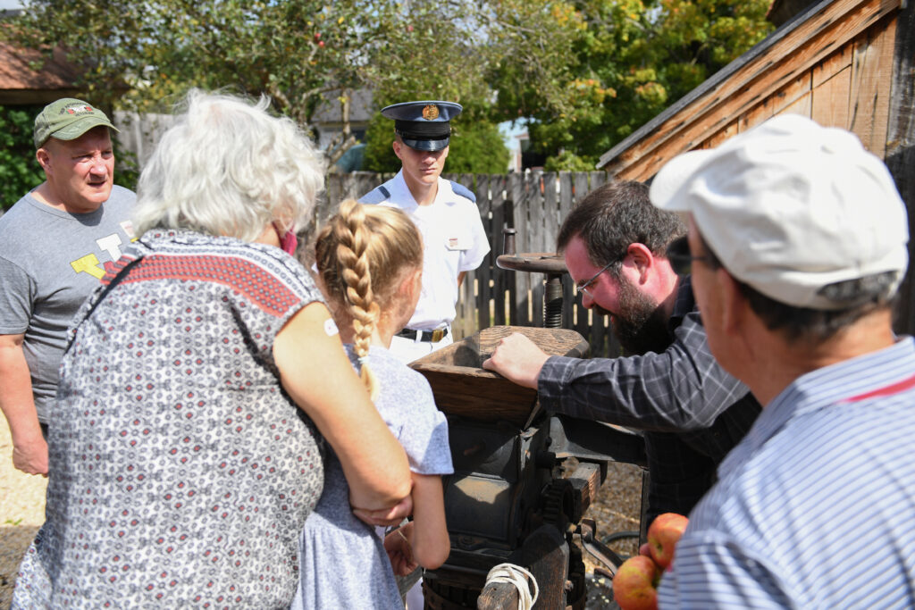 Attendees observe an apple press deomnstration.