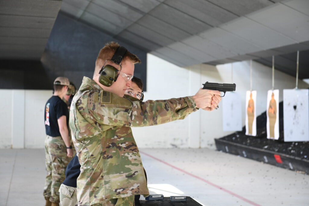 Cadets shoot guns in a shooting range.