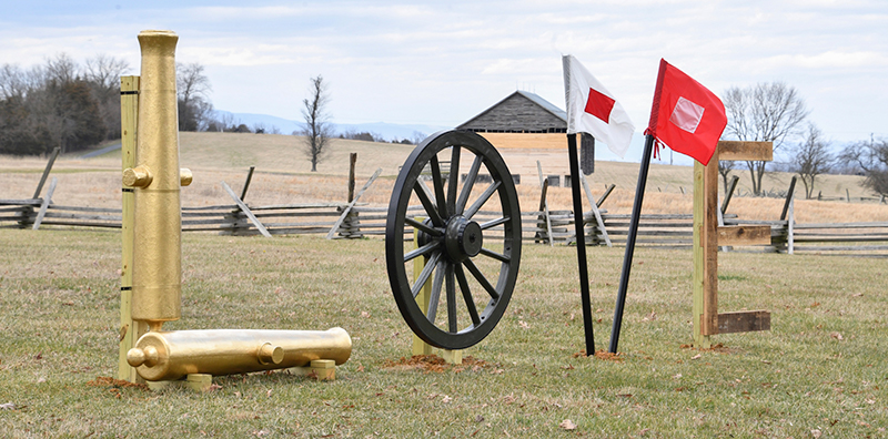 L O V E spelled out with cannon, wheel, flags, and wood.