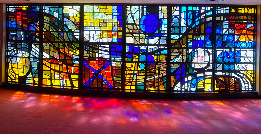 Light streaming through the 28-foot-long slab glass window, featuring a variety of blues, yellows, and reds.
