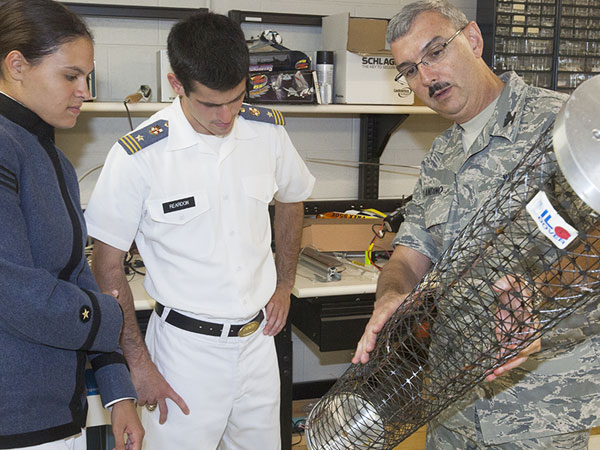 Cadets and faculty member inspect equipment.