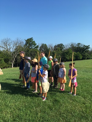 Children in a group practicing military formations during summer camp.