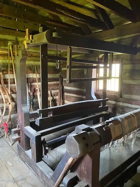 Loom from the 1800s sitting inside a wooden house.